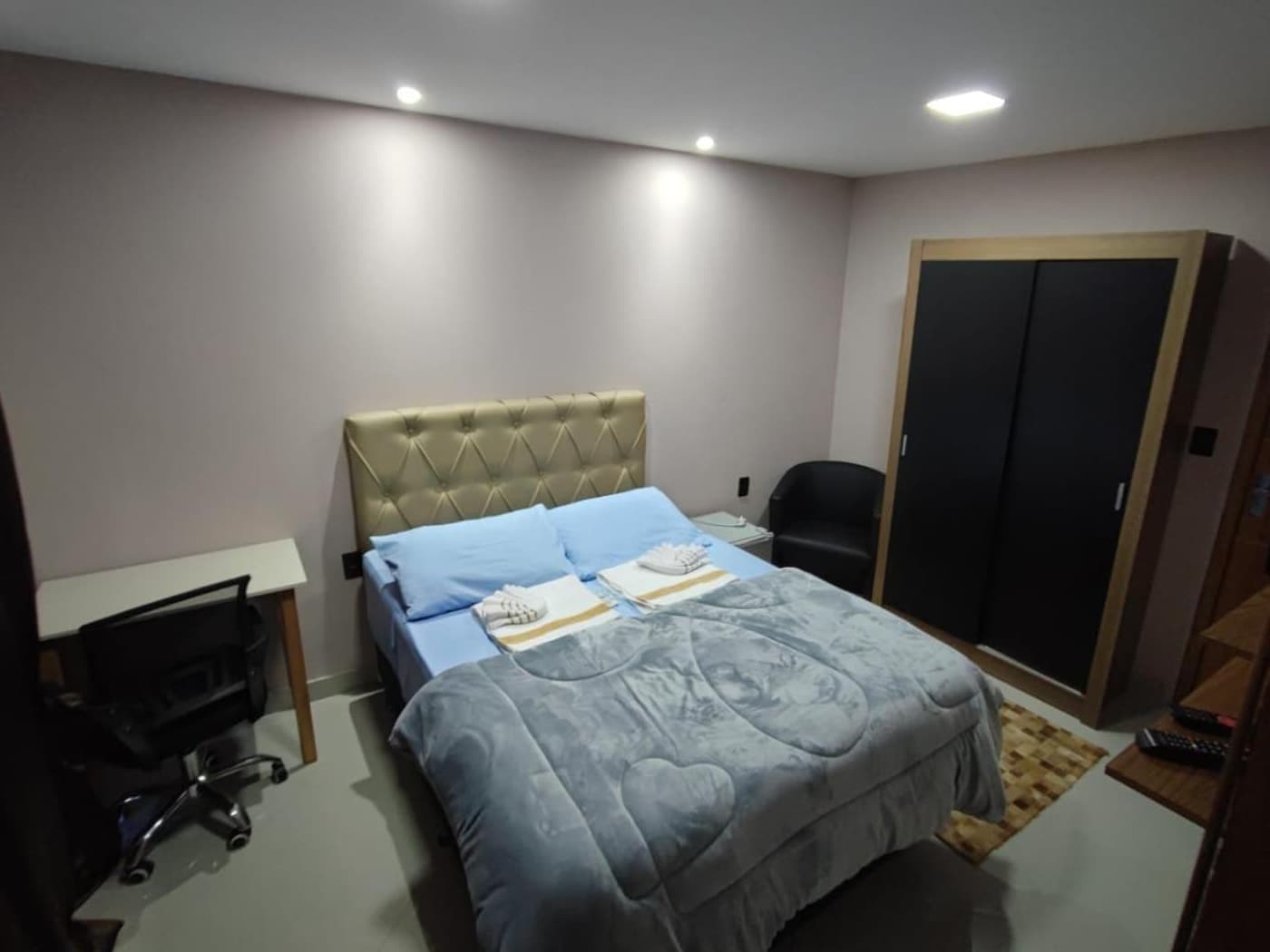 Quarto de casal com cama, mesa de trabalho e guarda-roupa