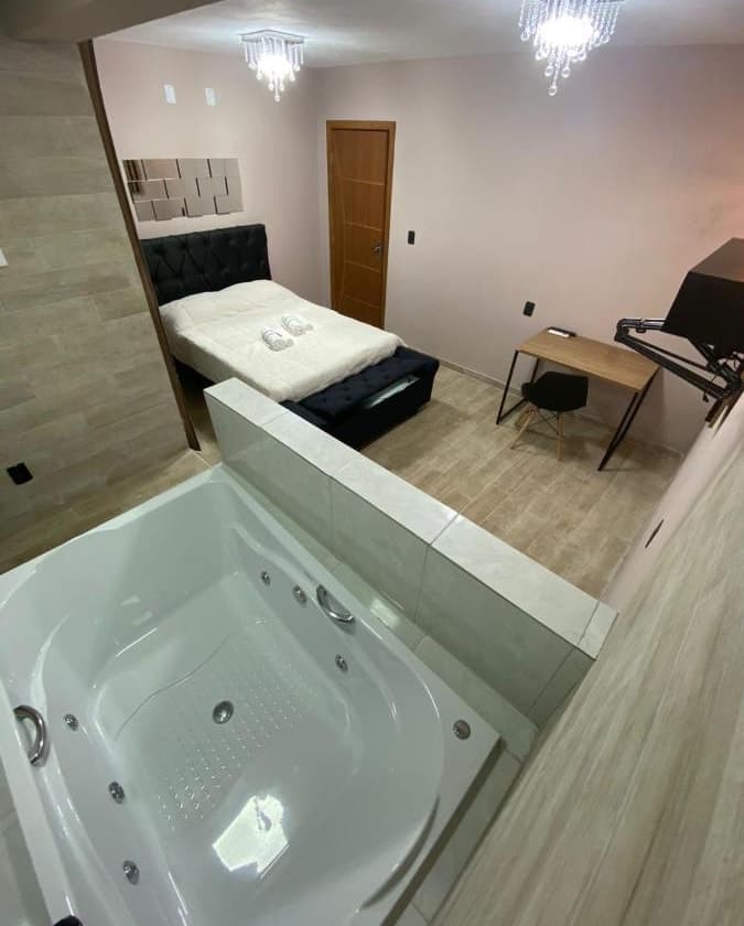 Suíte com banheira de hidromassagem e cama de casal ao fundo